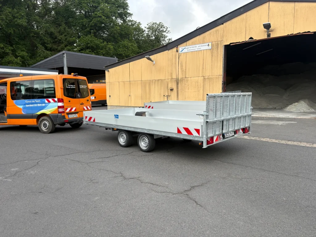 Maschinentransporter mit kippbarer Ladefläche und Gitteraufsatz auf einem Bauhof